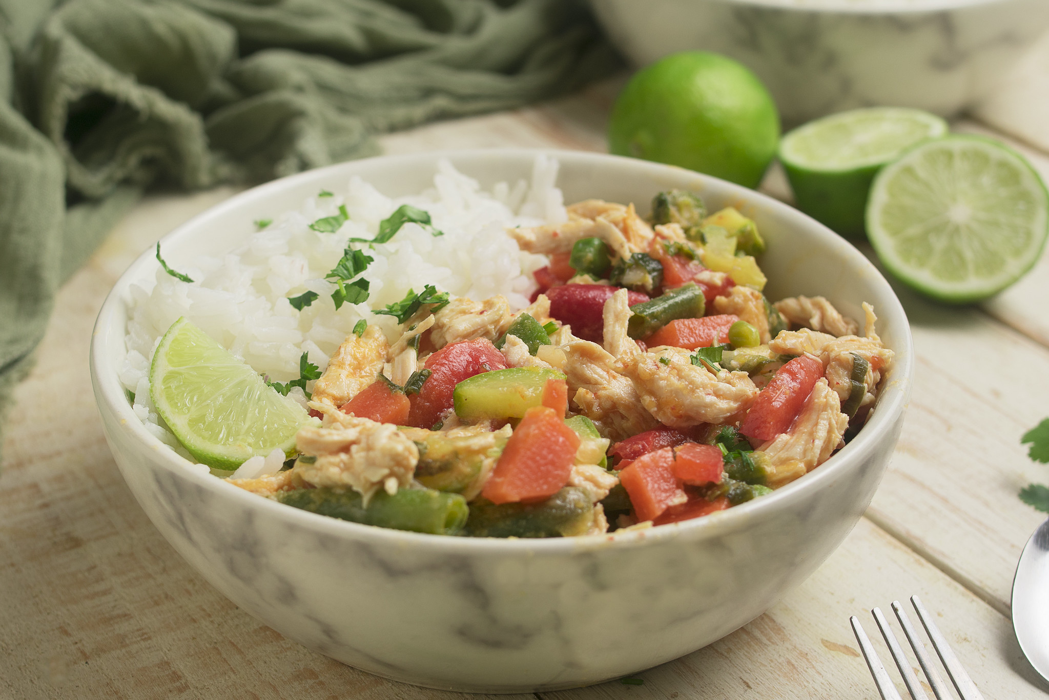 Thai-inspired chicken curry with mixed vegetables, jasmine rice and a lime wedge.